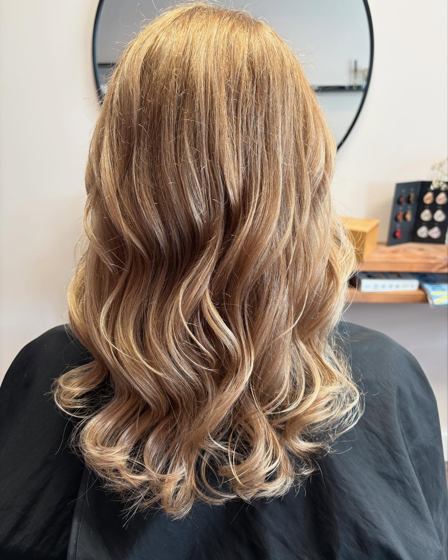 Lang golvend karamelblond haar voor de ronde spiegel
