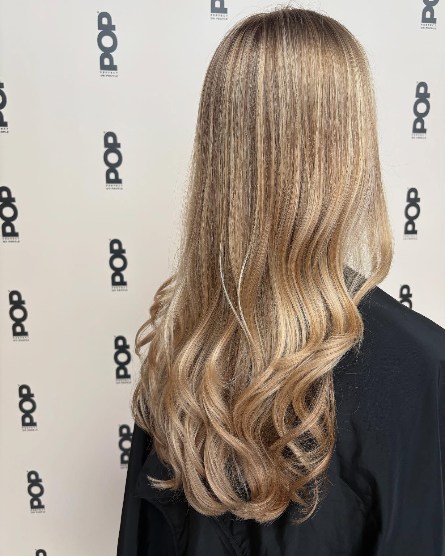Lang blond haar met balayage voor een wand met het POP-logo